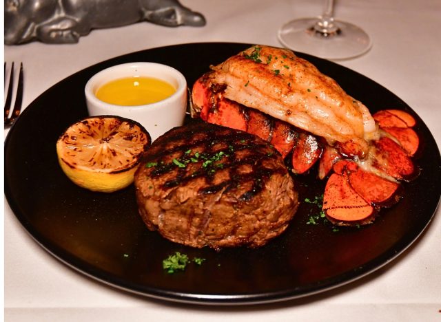 morton's steakhouse filet and lobster tail on a plate with a grilled lemon