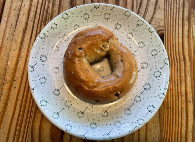 a panera blueberry bagel on a printed plate.