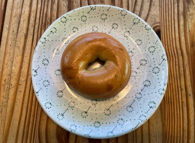 a panera plain bagel on a printed plate.