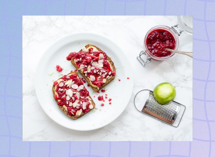 raspberry almond butter toast on white plate with mason jar of jam next to the plate