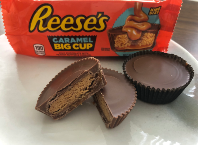 reeses caramel big cup broken open in front of a wrapper.