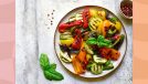 colorful roasted vegetables on a plate with small bowl of pepper on the side