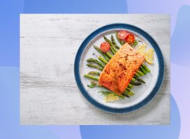 plate with grilled salmon, asparagus, and tomatoes on gray wood table