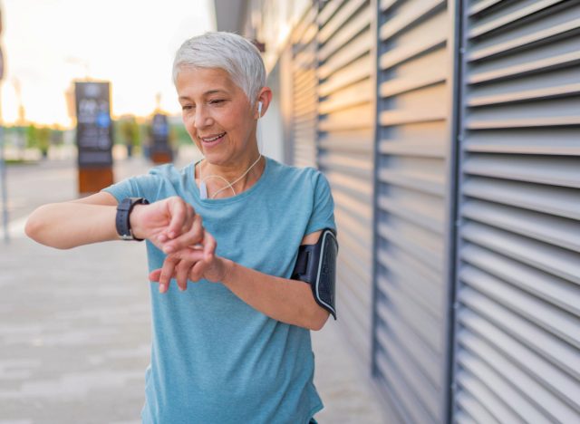 senior woman looking at fitness tracker while on a walk