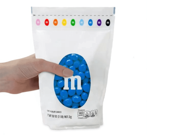 a hand holding a bag of blue m & m's.