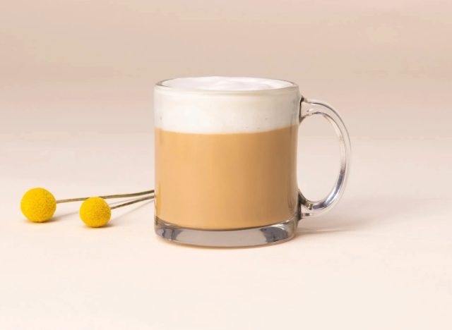 a mug of starbucks blonde vanilla latte on a plain background with a yellow garnish.