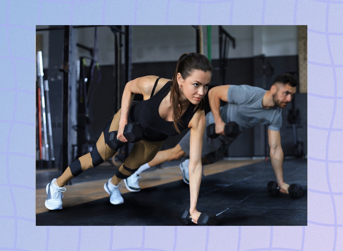 strong brunette woman at the gym doing renegade row exercise with dumbbells next to muscular man in a fitness class