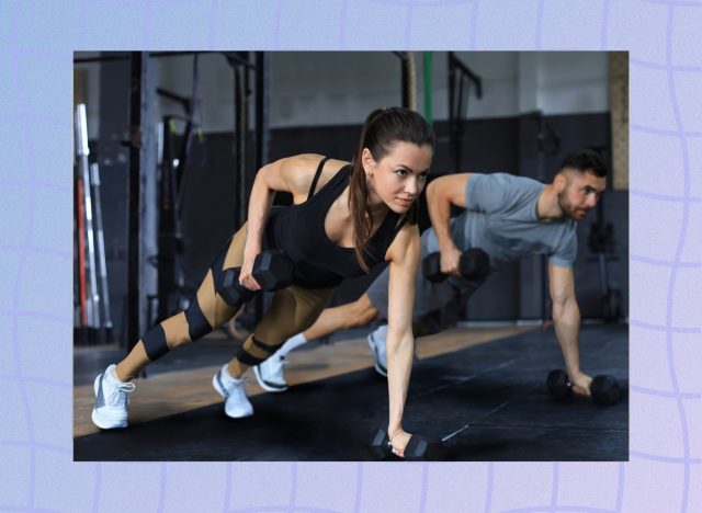 strong brunette woman at the gym doing renegade row exercise with dumbbells next to muscular man in a fitness class