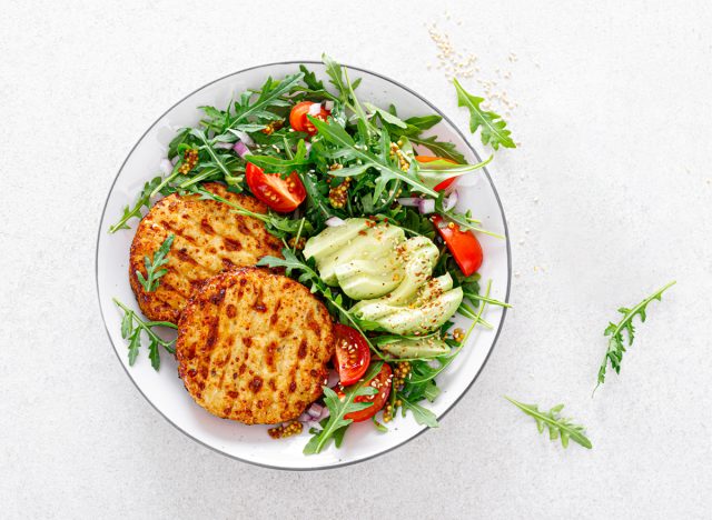 turkey burgers over arugula salad with sliced avocado