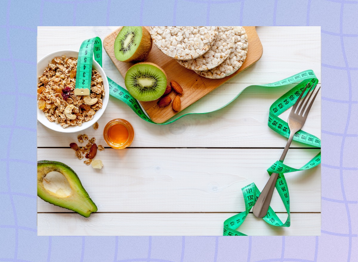 weight-loss diet concept, tape measure, rice cakes, granola, and kiwi on cutting board and white table