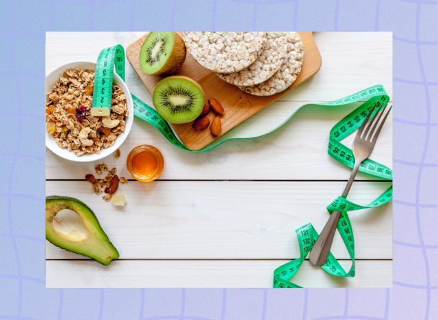 weight-loss diet concept, tape measure, rice cakes, granola, and kiwi on cutting board and white table