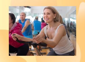 mature blonde woman with short hair wearing white tank top on indoor cycling bike in exercise class at the gym