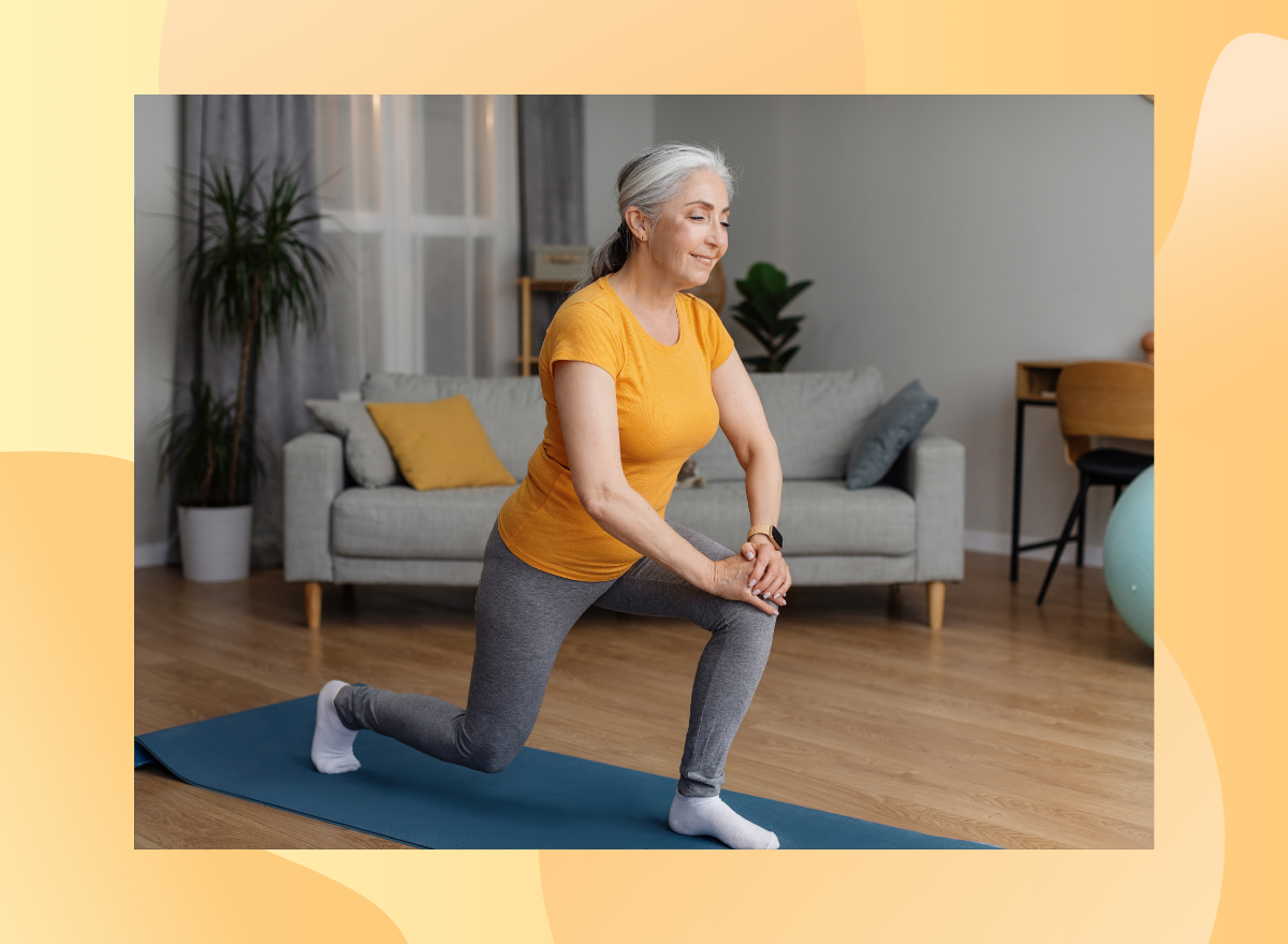 mature woman wearing orange shirt and grey leggings does hip flexor lunge stretch on yoga mat in her living room