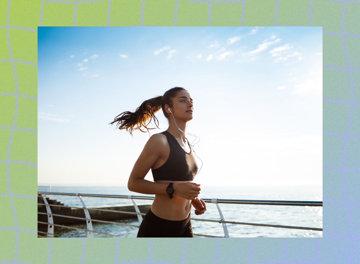 fit brunette woman in black sports bra and leggings running outdoors on boardwalk by the water on sunny day