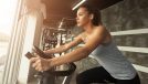 fit woman riding on a stationary bike at the gym, looking out a window