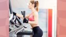 fit woman in pink sports bra using the elliptical at the gym