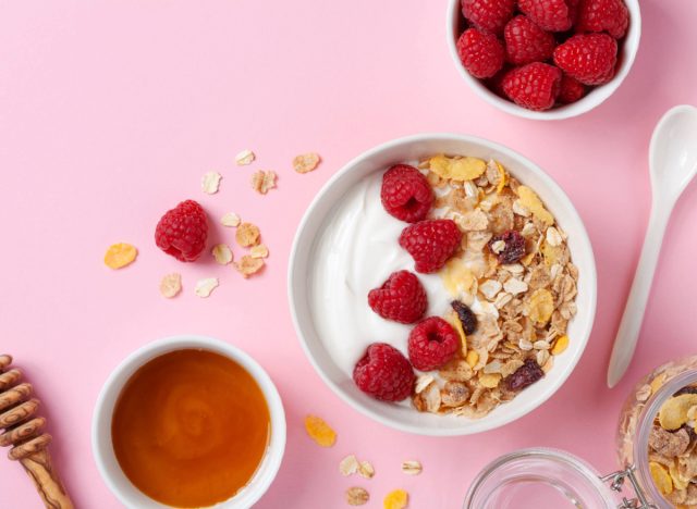 yogurt in bowl with raspberries and honey on pink surface