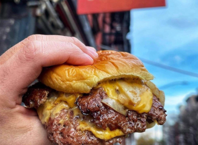 a hand holding a 7th street cheeseburger.