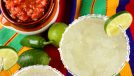 A classic margarita with salted rim glass and ramekin of salsa on a colorful table cloth