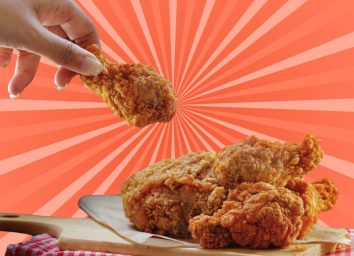 Woman holding a drumstick over a plate of hot fried chicken against a colorful background