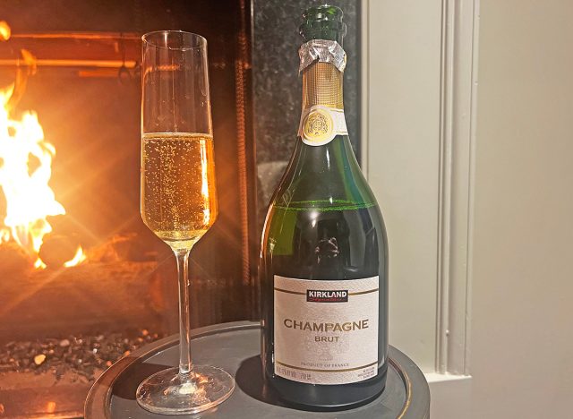 Costco's kirkland signature champagne bottle and glass by fireplace.