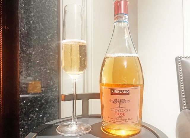 A bottle and glass of Costco's Kirkland Signature prosecco rose on a table.