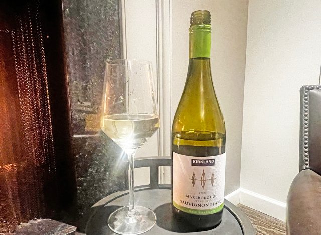 Costco's kirkland signature sauvignon blanc glass and bottle on a table.