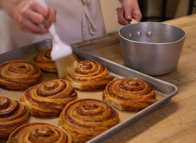A baker brushes the final touches of simple syrup and sugar on a Roulé Cannelle at Le Panier in Seattle.