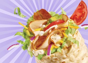 A closeup of the new Turkey, Bacon & Avocado flatbread wrap at Subway, against a colorful background.