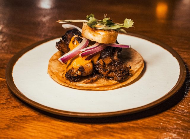 Pork belly, red onions, cilantro, habanero salsa, and tequila grilled pineapple on a taco at Ni Tuyo