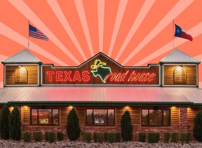 Storefront of a Texas Roadhouse restaurant against a colorful background