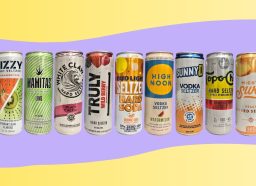a photo of nine popular hard seltzer cans in a line on a wavy yellow and purple designed background