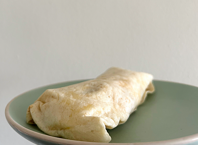 a carl's jr breakfast burrito on a green plate. 