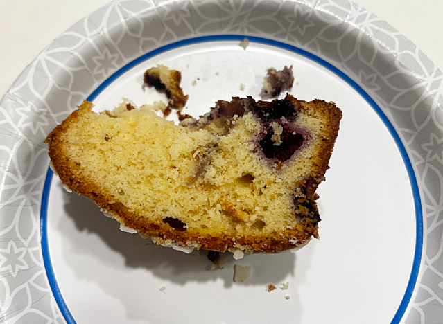 a half eaten slice of lemon blueberry loaf on a paper plate.