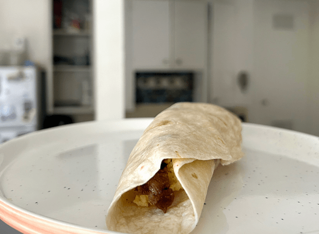 del taco burrito on a white plate in a kitchen.