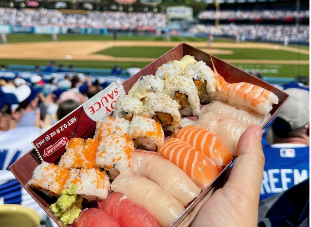 a hand holding a tray of sushi at dodger stadium.