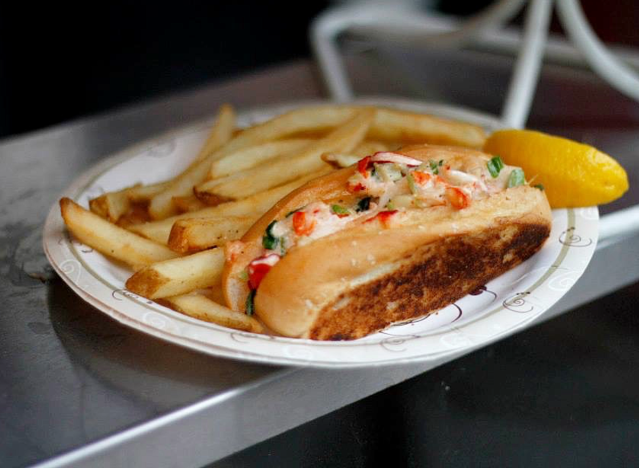 a clam roll and fries on a plate at fenway park.