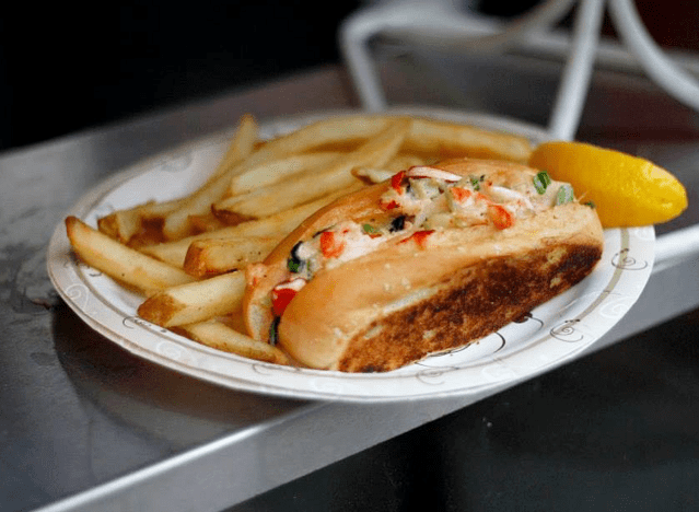 a clam roll and fries on a plate at fenway park.