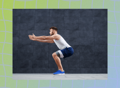 fit, muscular man doing squats outdoors in front of black wall on pavement