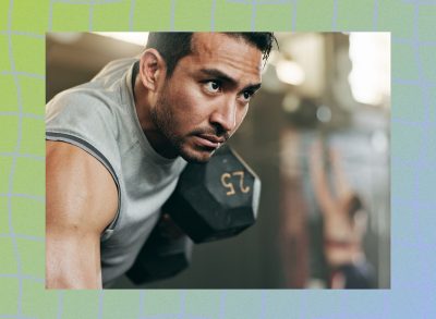 fit, focused man at the gym lifting heavy dumbbell