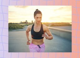 fit brunette woman in pink shorts and black sports bra running outdoors at sunset