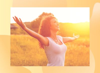 happy woman with curly hair in the sunshine in meadow