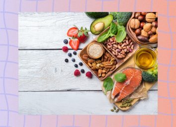 healthy fats like avocado, salmon, olive oil, and nuts on white wood table