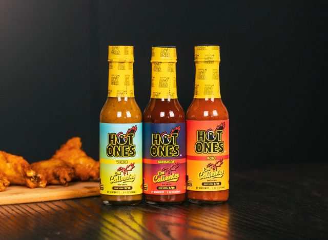 bottles of hot ones hot sauces next to chicken wings