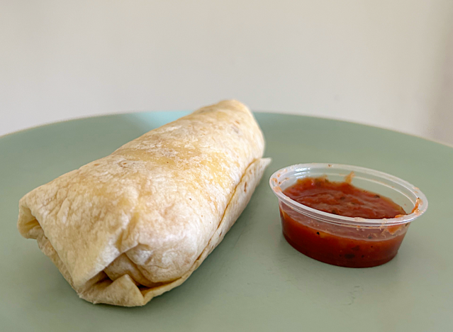 a jack in the box meat lovers burrito with dipping sauce on a green plate. 