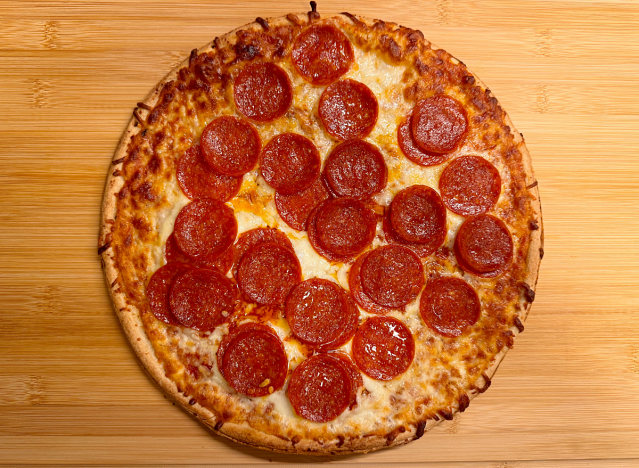 a pepperoni pizza ona cutting board. 