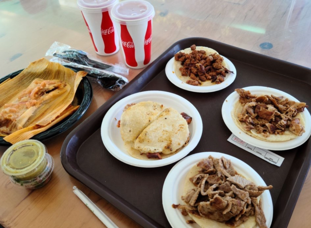 tacos on takeout plates on a tray.