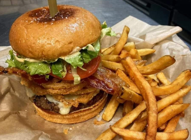 a huge burger from main street grill with fries on the side.