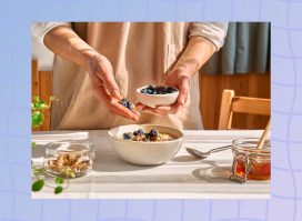 close-up of woman's hands adding blueberries to oatmeal breakfast in bright kitchen
