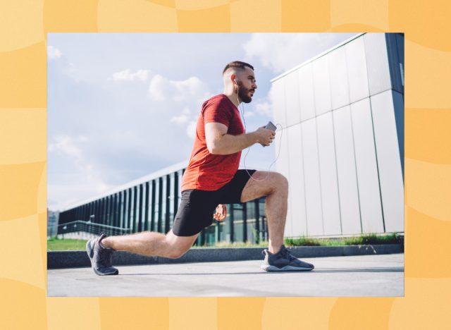 fit man doing walking lunges outdoors while listening to music on phone